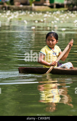 Les jeunes autochtones indigènes Garifuna indiens girl paddling une pirogue sur le lac d'Izabal, Lago de Izabal, Guatemala. Banque D'Images