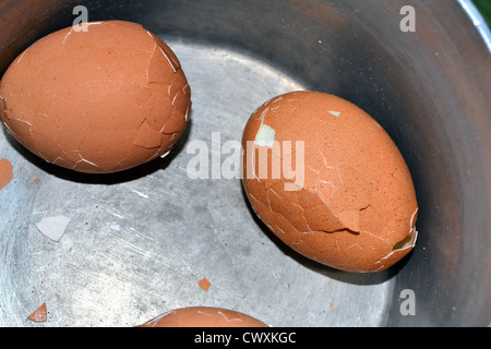 Trois oeufs durs dans une casserole avec des coquilles fêlées Banque D'Images