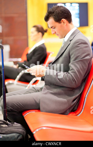 Businessman de l'envoi ou la lecture de messages texte à l'aéroport Banque D'Images