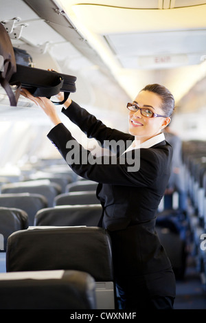 Pretty woman mettant son assurance en compartiment au on airplane Banque D'Images