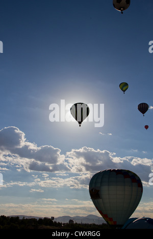 Hot Air Balloon obscurcissant le soleil du matin est silhouetté contre le ciel. D'autres ballons sont tout autour. Banque D'Images