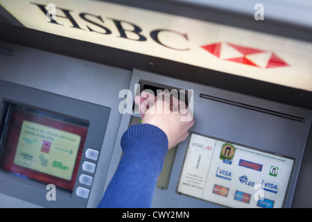 Les femmes de l'insertion d'une carte de débit en un point en argent de la HSBC pour retirer de l'argent Banque D'Images
