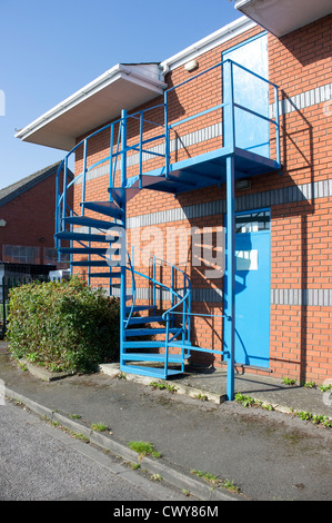 Acier peint en bleu en colimaçon fire escape sur le côté du bâtiment industriel Banque D'Images