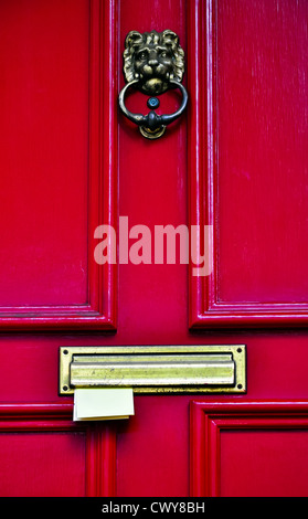 Porte en bois rouge avec les heurtoirs en laiton et coller des lettres dans la boîte aux lettres Banque D'Images