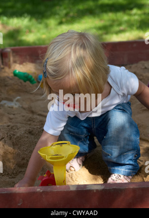 Enfant Bébé fille blonde jouant dans l'été de sandbox Banque D'Images