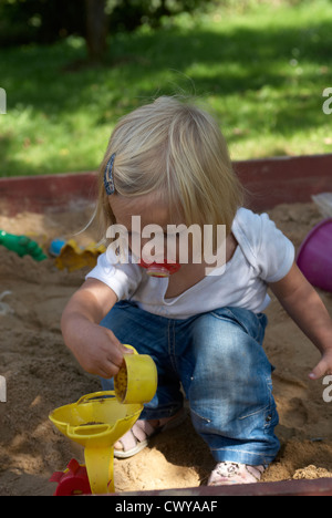 Enfant Bébé fille blonde jouant dans l'été de sandbox Banque D'Images