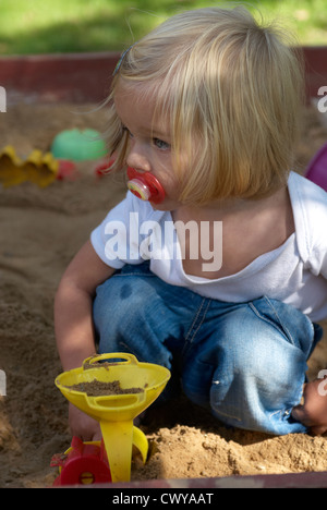 Enfant Bébé fille blonde jouant dans l'été de sandbox Banque D'Images