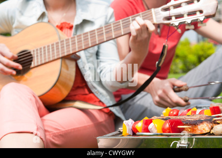 Couple barbecueing et jouer de la guitare Banque D'Images
