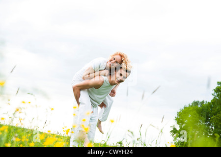 Young man carrying girlfriend piggyback Banque D'Images