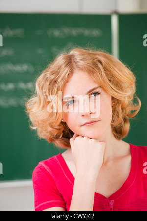 Thoughtful teenage girl in classroom, portrait Banque D'Images