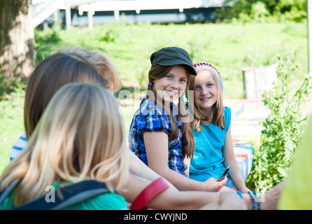 Cinq filles assis sur un banc avec cell phone Banque D'Images