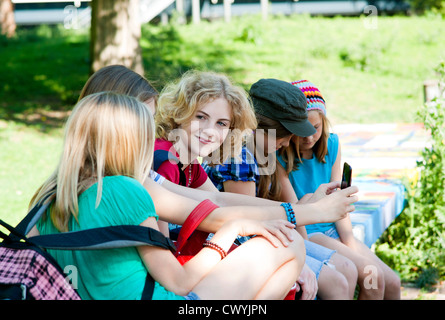 Cinq filles assis sur un banc avec cell phone Banque D'Images