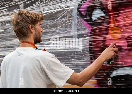 Un graffiti peintre peint un bus pendant un festival de rue à Copenhague, Danemark Banque D'Images