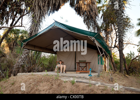 Une touriste sur la véranda de sa tente, le lac Manze tented safari camp, Selous Tanzanie Afrique Banque D'Images