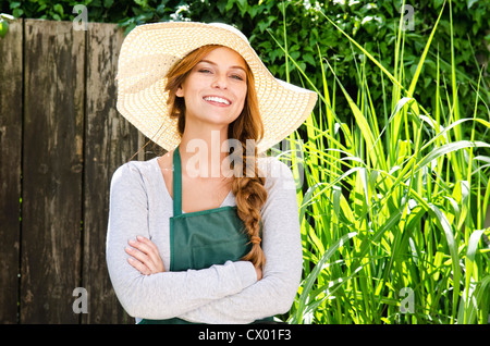 Smiling young woman wearing sunhat et un tablier de jardin Banque D'Images