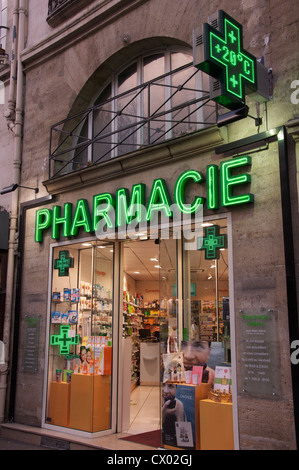 Les lumières lumineuses et propres conception clinique d'une pharmacie française high street, avec ses enseignes néon vert et clignotant des croix. Paris, France. Banque D'Images