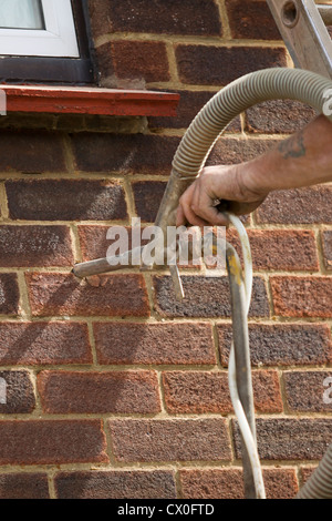 Bille de polystyrène de pompage l'isolation des murs creux dans suburban house au Royaume-Uni Banque D'Images