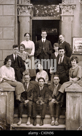 Un groupe d'amis et de la famille assise sur les marches d'une maison de pension à la mer dans les années 1920. Banque D'Images