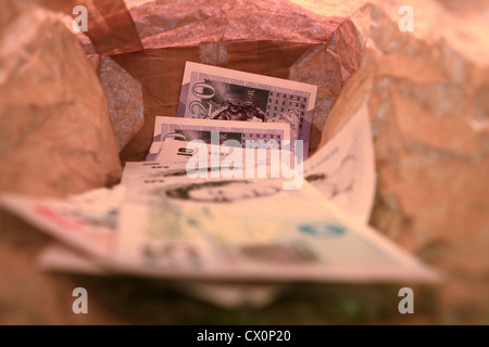 Sterling notes dans un sac en papier brun Banque D'Images