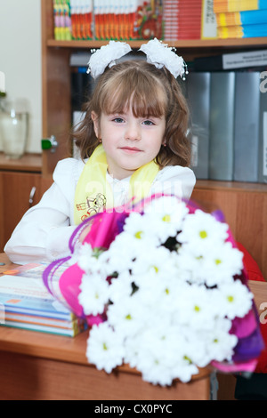 Jeune fille russe avec des fleurs assis au bureau dans une leçon en première année à l'école primaire. Saint-pétersbourg, Russie. Banque D'Images