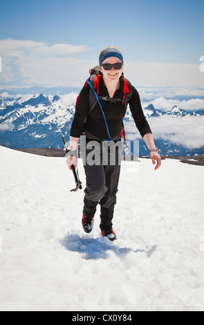 Portrait d'une jeune femme comme elle la fait grimpeur chemin jusqu'à la neige Muir champ sur le Mont Rainier, Washington State, USA. Banque D'Images
