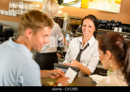 Couple paying bill au café caisse smiling waitress bar Banque D'Images