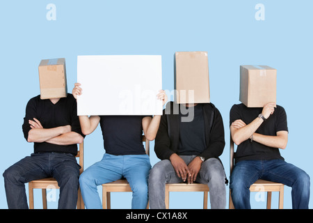 Man holding blank carton avec Visages amis masculins couverts avec des cases sur fond bleu Banque D'Images