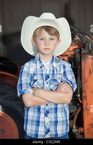 Portrait d'un petit garçon wearing cowboy hat en position debout avec les bras croisés contre la machine Banque D'Images