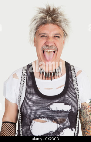 Portrait de senior male punk sticking out tongue sur fond gris Banque D'Images