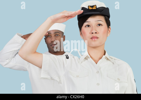 Portrait d'une femme officier de la Marine US et plus de salut marin mâle fond bleu clair Banque D'Images