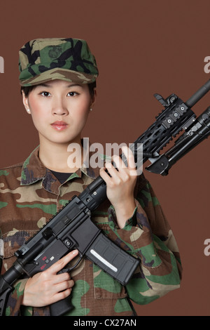 Portrait de belle jeune soldat de l'US Marine Corps avec fusil d'assaut M4 sur fond brun Banque D'Images