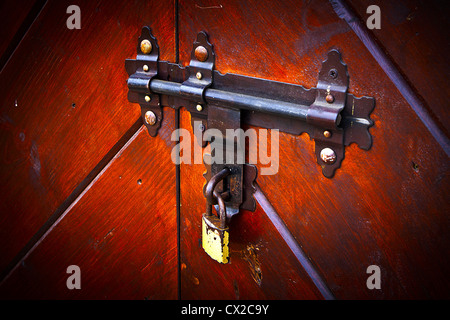Ancienne serrure rouillée, le loquet sur la porte fermé avec un cadenas moderne. Banque D'Images