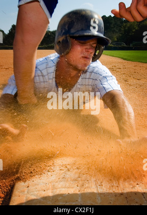 Un port du casque college baseball player glisse dans la troisième base sur un terrain de l'école Banque D'Images