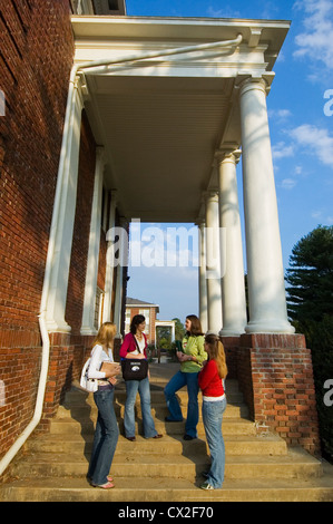 Rencontrez quatre étudiantes entre les classes sur les marches d'un bâtiment de classe du collège. Banque D'Images