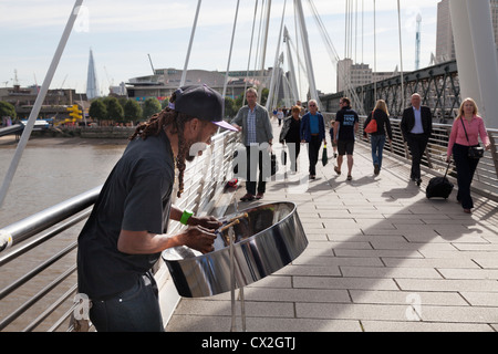 Musicien ambulant jouant le steel band drum (tambour métallique) sur le Jubilé passerelle au-dessus de la Tamise par Hungerford Bridge. Banque D'Images