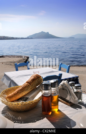 Une table dressée pour un repas dans une taverne grecque avec du pain et des bouteilles d'huile et vinaigre Banque D'Images