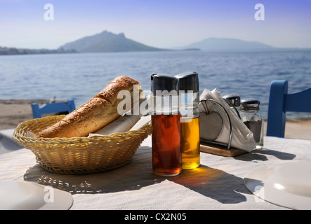 Une table dressée pour un repas dans une taverne grecque avec du pain et des bouteilles d'huile et vinaigre Banque D'Images