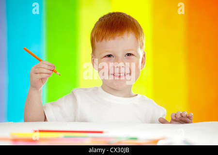 Red-haired boy adorable dessin avec crayon orange sur fond arc-en-ciel Banque D'Images