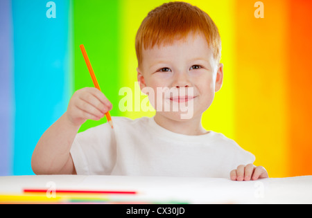 Red-haired boy adorable dessin avec crayon orange sur fond arc-en-ciel Banque D'Images