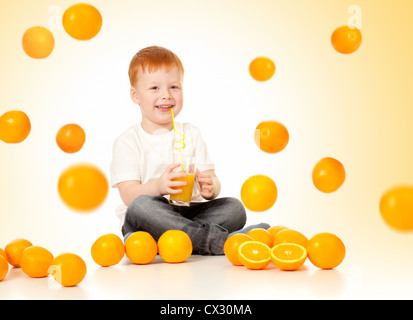 Garçon roux avec la chute des oranges et le jus d'orange Banque D'Images