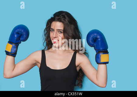 Portrait d'une belle jeune femme boxer raising arms dans la victoire contre fond bleu Banque D'Images