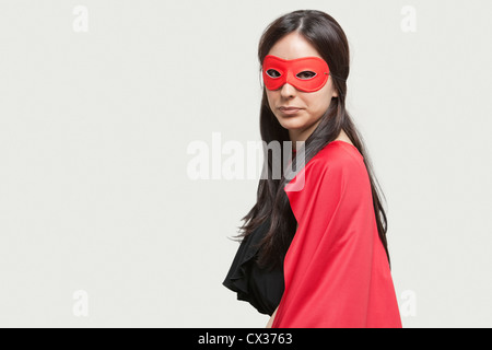 Portrait de jeune femme en costume de super-héro contre l'arrière-plan gris Banque D'Images