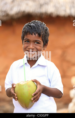 Jeune Indien boy drinking from une noix de coco l'Andhra Pradesh en Inde du Sud Banque D'Images