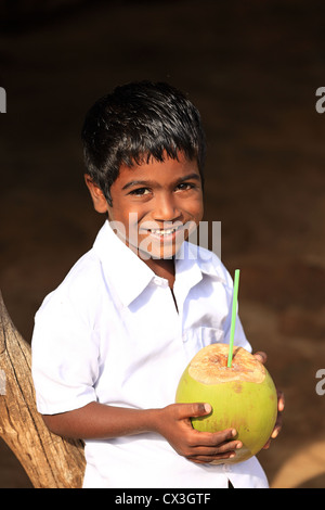 Jeune Indien boy drinking from une noix de coco l'Andhra Pradesh en Inde du Sud Banque D'Images