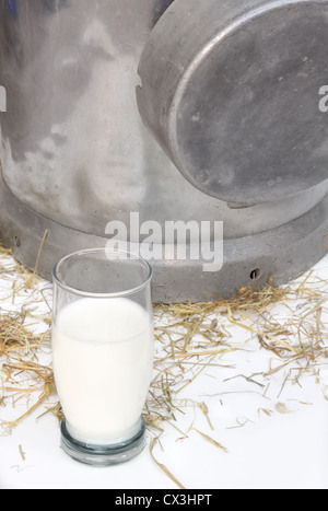Verre de lait en face d'un contenant de métal sur la paille Banque D'Images
