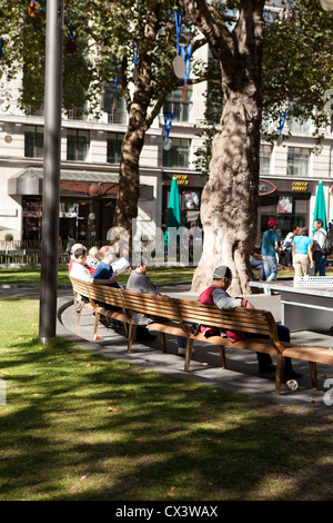 Des gens assis sur les bancs dans le nouveau Leicester Square à Londres Banque D'Images