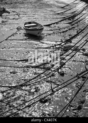 Image en noir et blanc de petit bateau à marée basse à Lyme Regis Port, Royaume-Uni. Banque D'Images