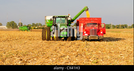 La récolte du maïs avec une moissonneuse-batteuse John Deere et le tracteur pour le transport des céréales et de déchargement de wagons de grain à un Diamond T camion antique Banque D'Images