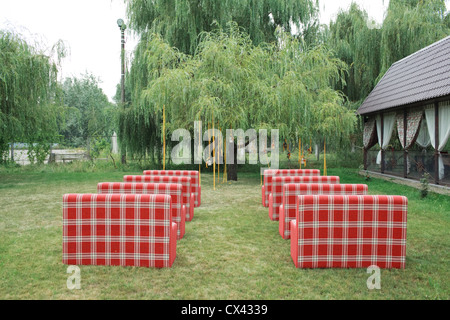 Des rangées de chaises vides rouge sur une pelouse avant un mariage ou une cérémonie Banque D'Images