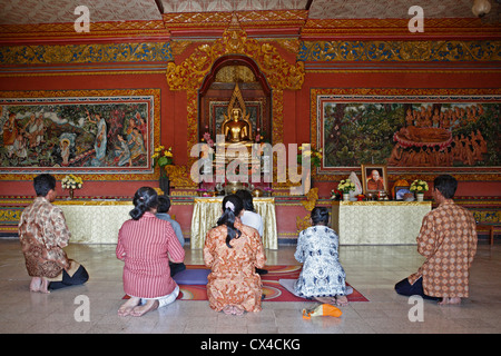 Les fidèles devant une statue de Bouddha en or dans l'une des chambres du culte Brahmavihara Arama monastère Bouddhiste. Banque D'Images